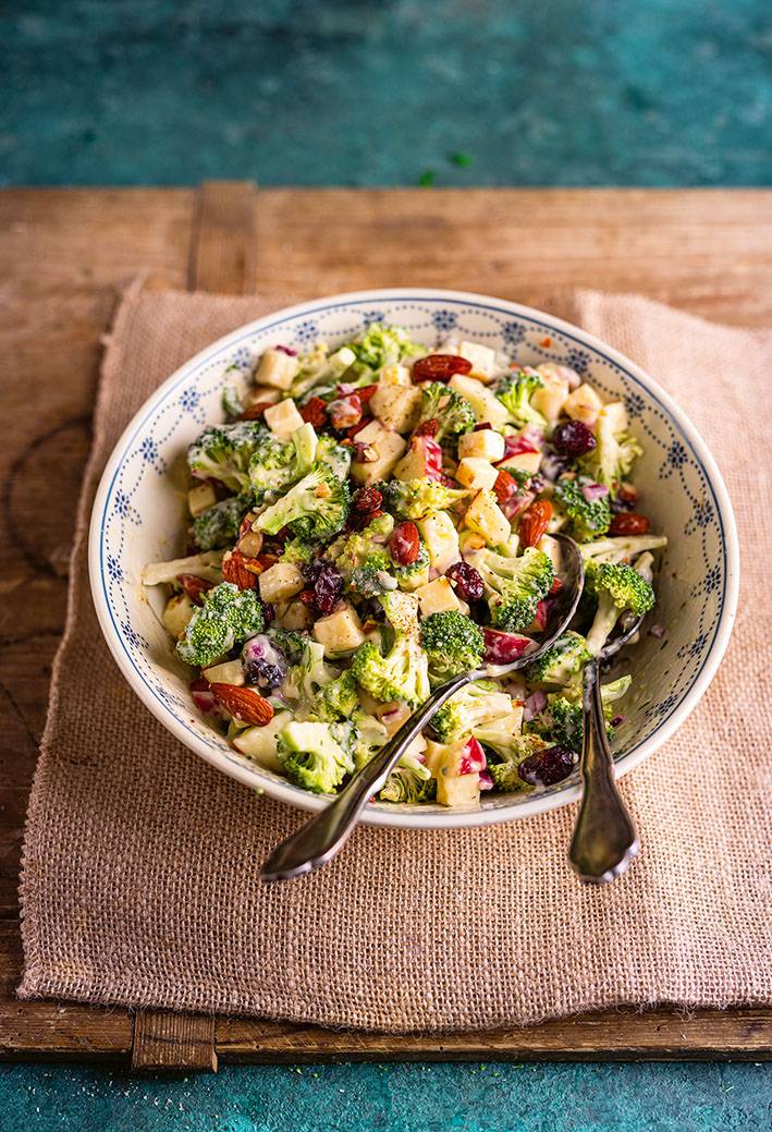 Teller mit Brokkolisalat, kleingehackten Äpfeln und Käsewürfeln